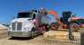 Loader moving sand toward large truck